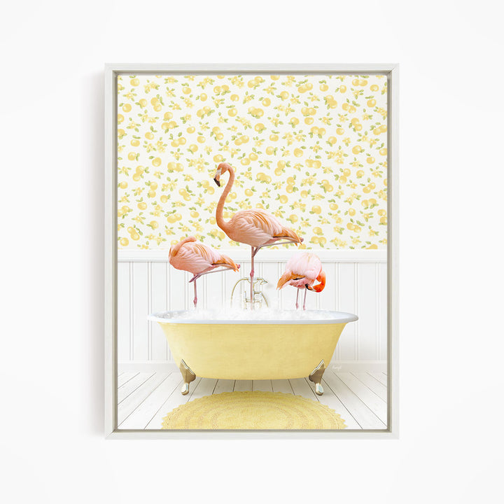 A framed image depicting three pink flamingos standing in a yellow bathtub, with a yellow and white floral wallpaper in the background.