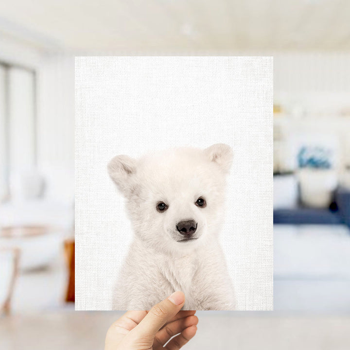 A hand is holding up a white polar bear against a white background.