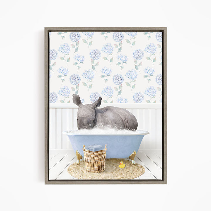 A rhinoceros is sitting in a blue bathtub filled with water, surrounded by a wicker basket and yellow rubber ducks.