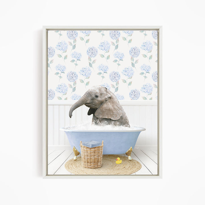 A baby elephant sitting in a blue bathtub filled with water, surrounded by a wicker basket and a yellow rubber duck.