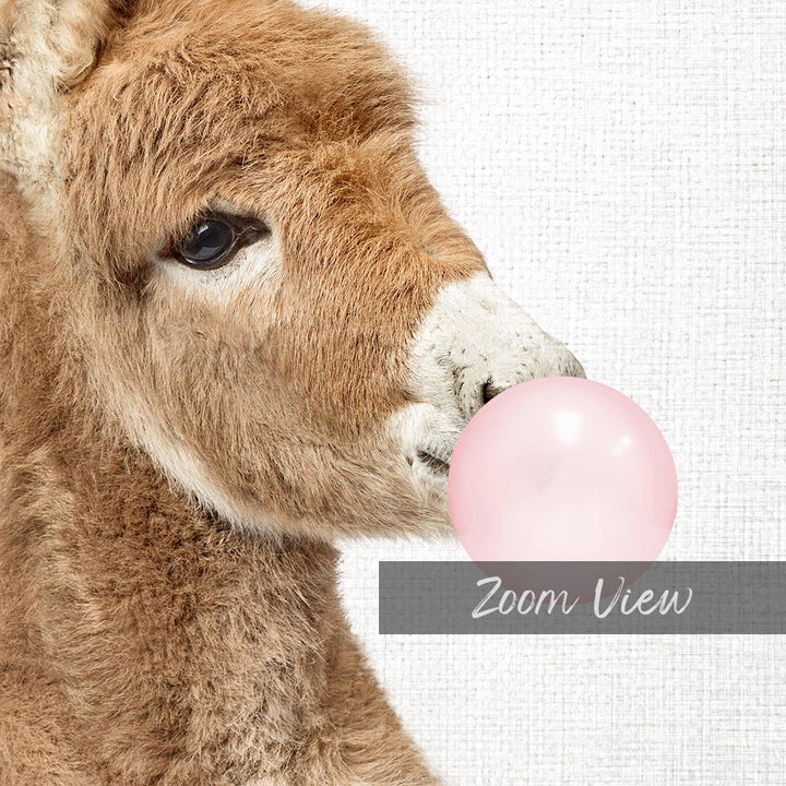 A close-up of a brown animal, possibly a donkey or a sheep, blowing a pink bubble with its mouth.