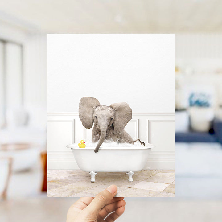A small elephant is sitting in a white bathtub, surrounded by a yellow rubber duck.