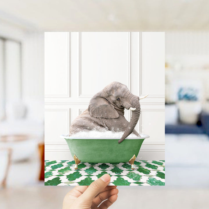 A gray elephant is sitting in a green bathtub filled with bubbles, surrounded by a green and white patterned floor.