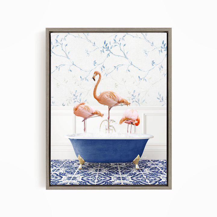 A framed image depicting three flamingos standing in a blue bathtub, with a patterned tile floor and a floral wallpaper in the background.