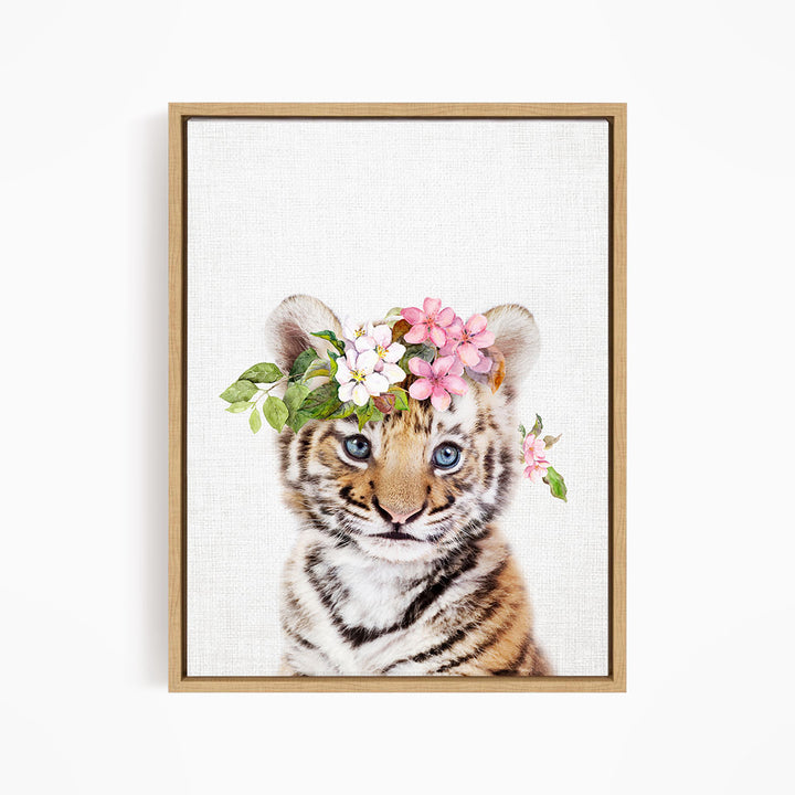 A young tiger cub wearing a floral crown on its head, with its eyes looking directly at the camera.