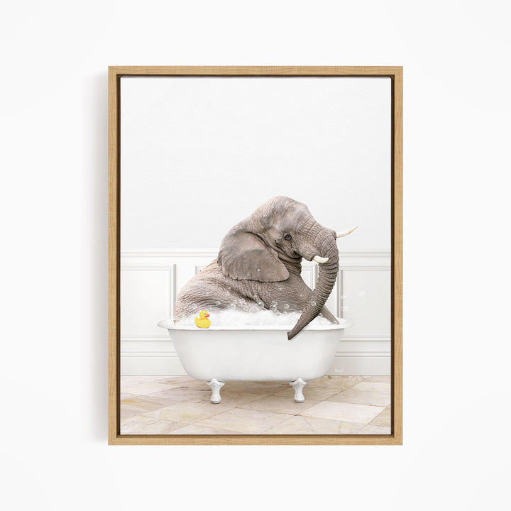 A gray elephant is sitting in a white bathtub, with a yellow rubber duck floating in the water.