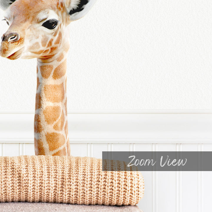 A giraffe peeking out from behind a beige blanket, with the text "Zoom View" overlaid on the image.