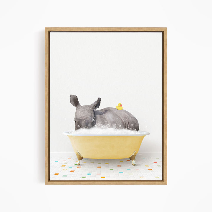 A rhinoceros is sitting in a yellow bathtub filled with bubbles, with a yellow rubber duck floating on its back.