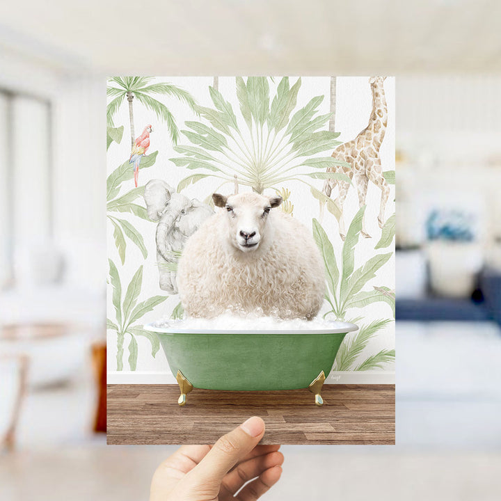 A hand holds up a framed image depicting a sheep sitting in a green bathtub, surrounded by tropical foliage and animals.