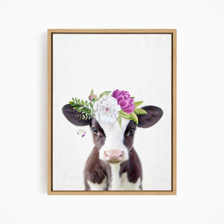 A framed print of a cow wearing a floral crown on its head.