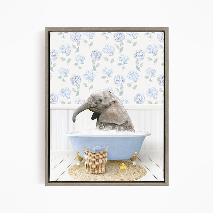 A gray elephant is sitting in a blue bathtub filled with water, surrounded by a wicker basket and yellow rubber ducks.