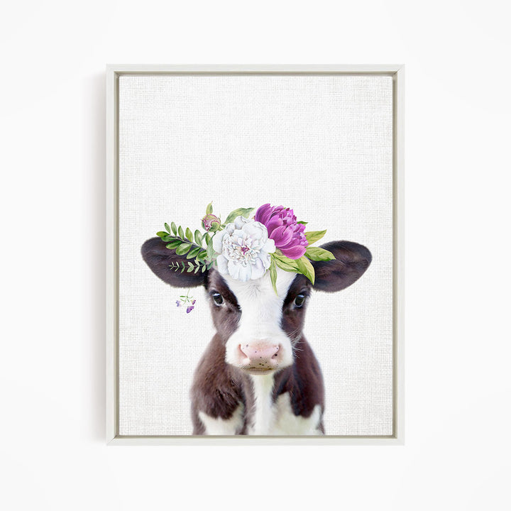 A framed print of a cow wearing a floral crown on its head.