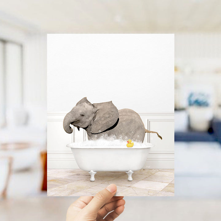 A gray elephant is sitting in a white bathtub filled with water, with a yellow rubber duck floating nearby.