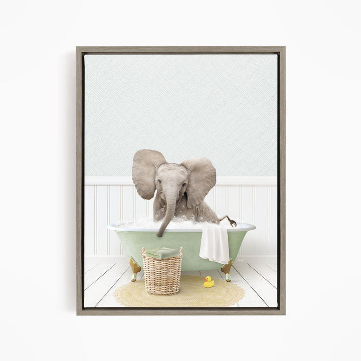 A gray elephant is sitting in a green bathtub filled with water, surrounded by a yellow rubber duck and a basket.