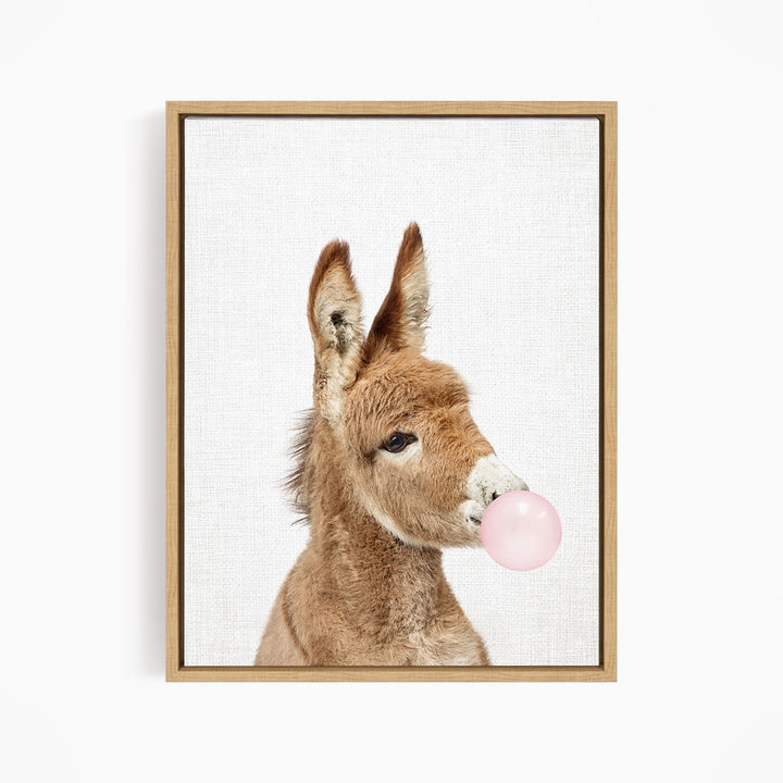 A donkey blowing a pink bubble with its mouth.