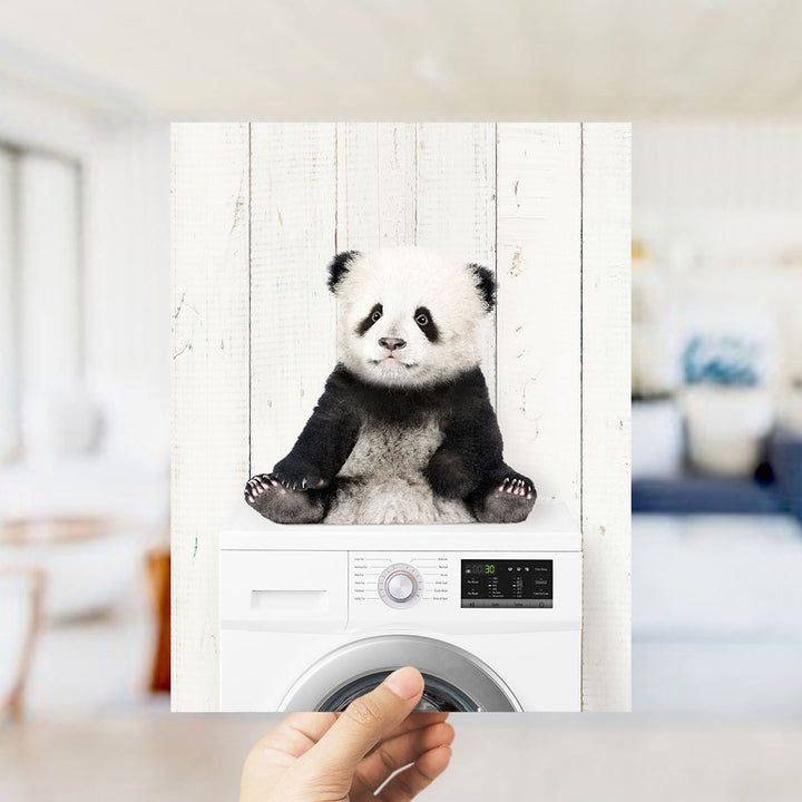 A panda bear sitting on top of a washing machine.