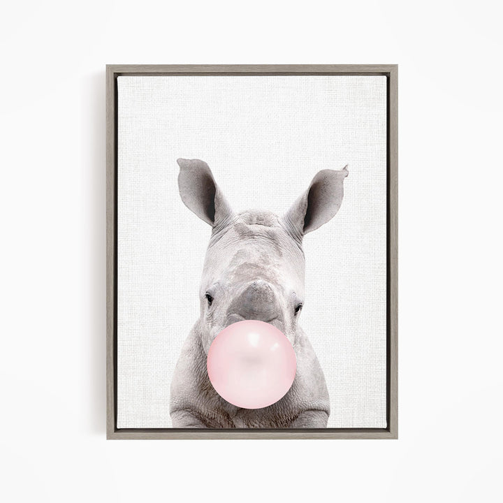 A rhinoceros blowing a pink bubble with its mouth.