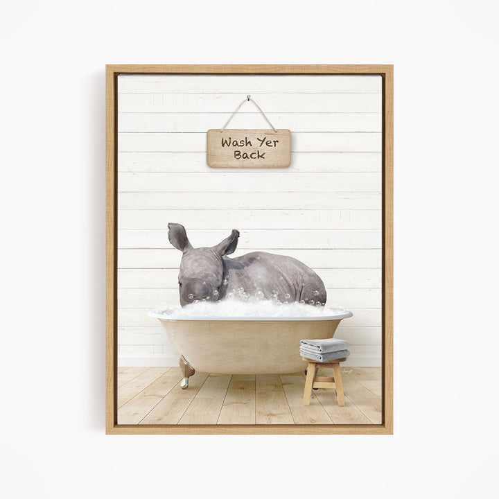A rhinoceros is sitting in a bathtub filled with water, with a wooden sign above it that says "Wash Yer Back".