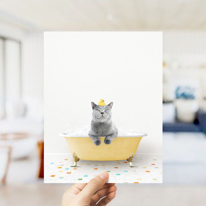 A gray cat sitting in a yellow bathtub, with a rubber duck on its head, is the main focus of the image.