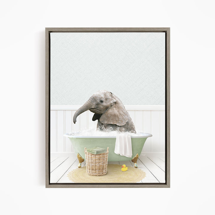 A gray elephant is sitting in a green bathtub filled with water, surrounded by a basket of toys and a yellow rubber duck.