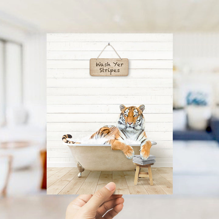 A hand holds up a framed photograph of a tiger sitting in a bathtub, with a sign above that reads "Wash Yer Stripes".