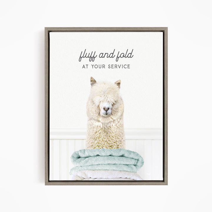 A fluffy alpaca sitting on a stack of light blue towels, with the text "fluff and fold at your service" written above the image.
