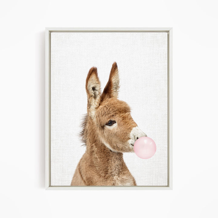 A donkey blowing a pink bubble with its mouth.