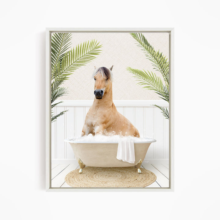 A light brown horse is sitting in a white bathtub filled with bubbles, surrounded by green palm leaves.