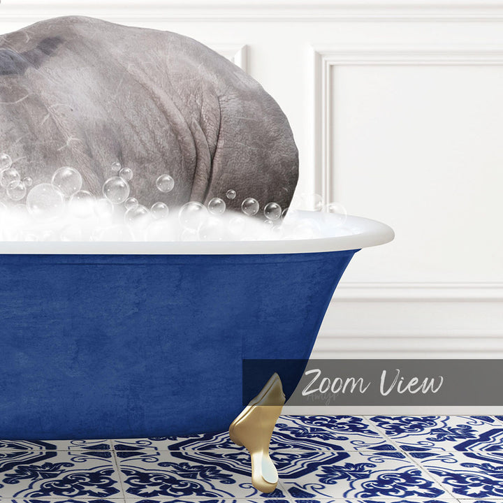A large gray rhinoceros is sitting in a blue bathtub filled with bubbles, with a gold bathtub leg visible on the floor.