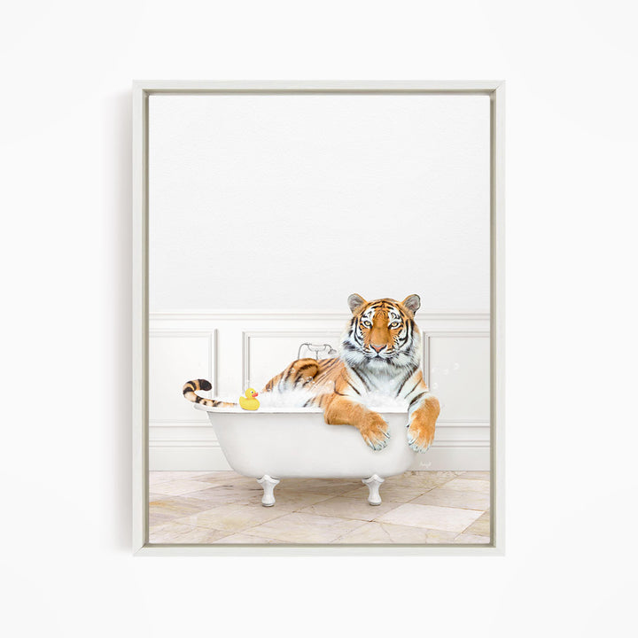 A tiger is sitting in a white bathtub, surrounded by a yellow rubber duck and a small toy.