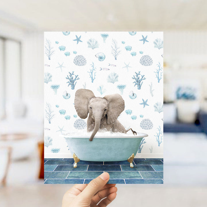 A hand is holding up a print featuring an elephant sitting in a bathtub filled with bubbles, surrounded by a blue and white ocean-themed background.