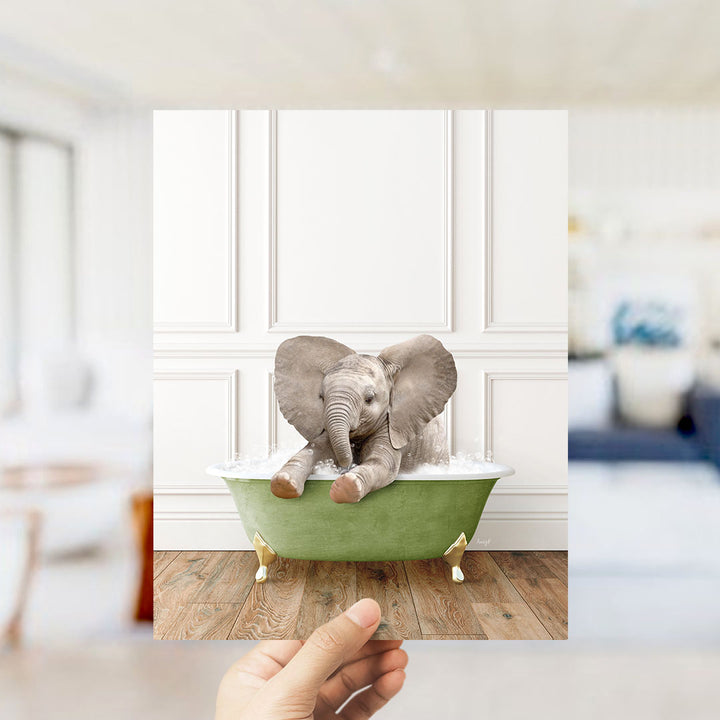 A small elephant sitting in a green bathtub, with its ears spread out, is the main focus of the image.