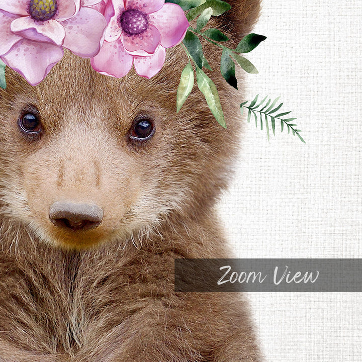 A close-up of a bear's face with a floral headpiece, featuring pink flowers and green leaves.