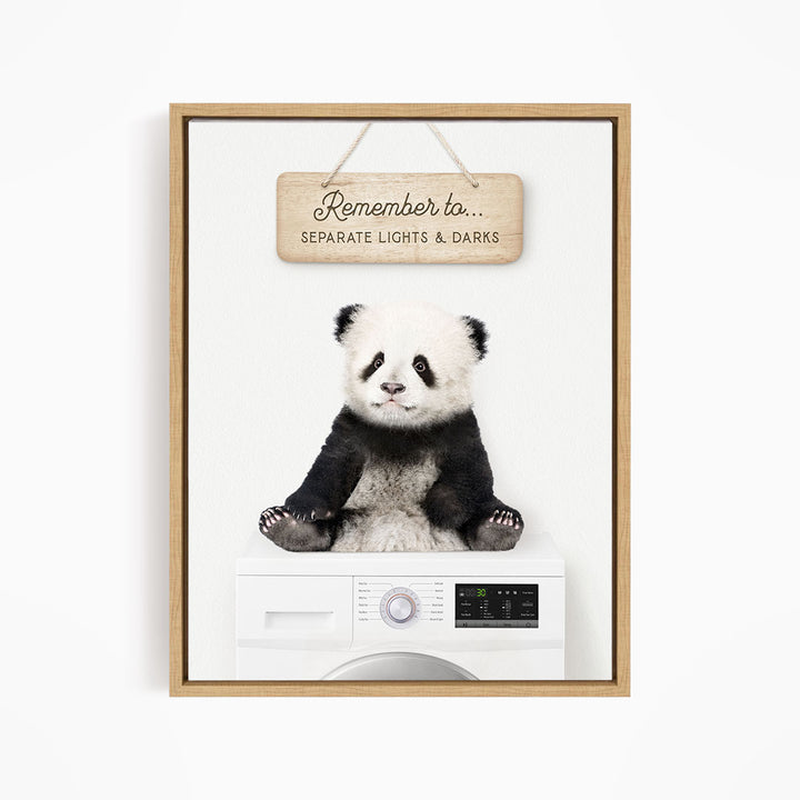 A panda bear sitting on top of a washing machine, with a wooden sign above that says "Remember to separate lights & darks".