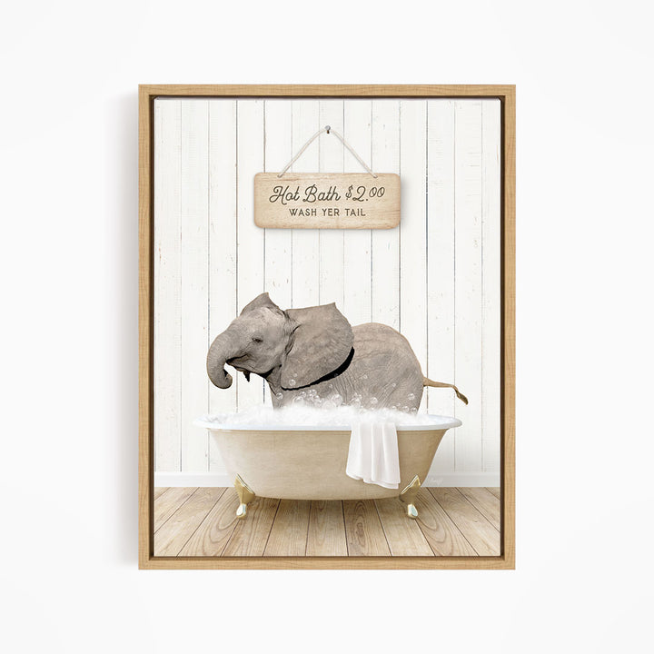 A framed image depicting a gray elephant sitting in a bathtub filled with water, with a sign above the bathtub that reads "Hot Bath $2.00 WASH YER TAIL".
