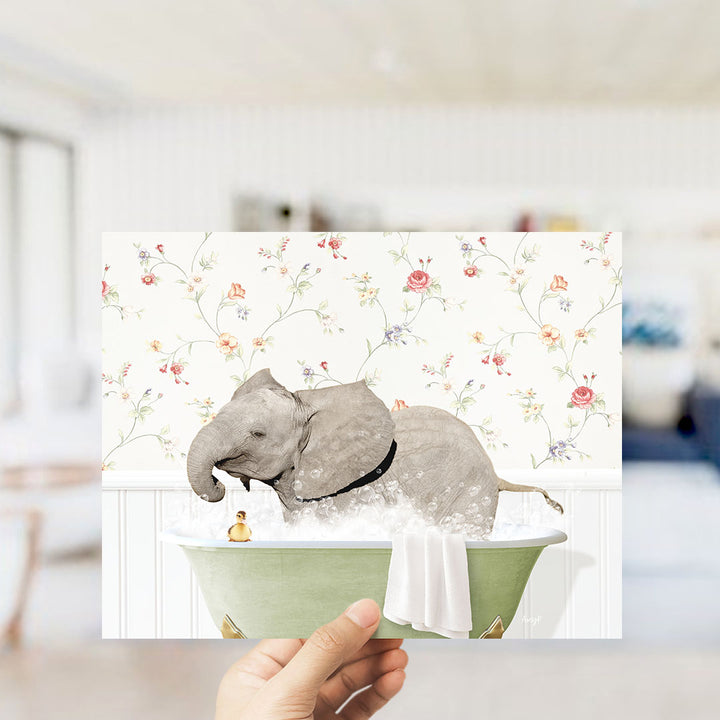 A hand holds up a collage of two images: an elephant sitting in a bathtub with a yellow rubber duck, and a floral wallpaper in the background.