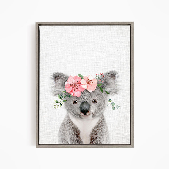 A gray koala bear wearing a floral headpiece with pink flowers and green leaves.