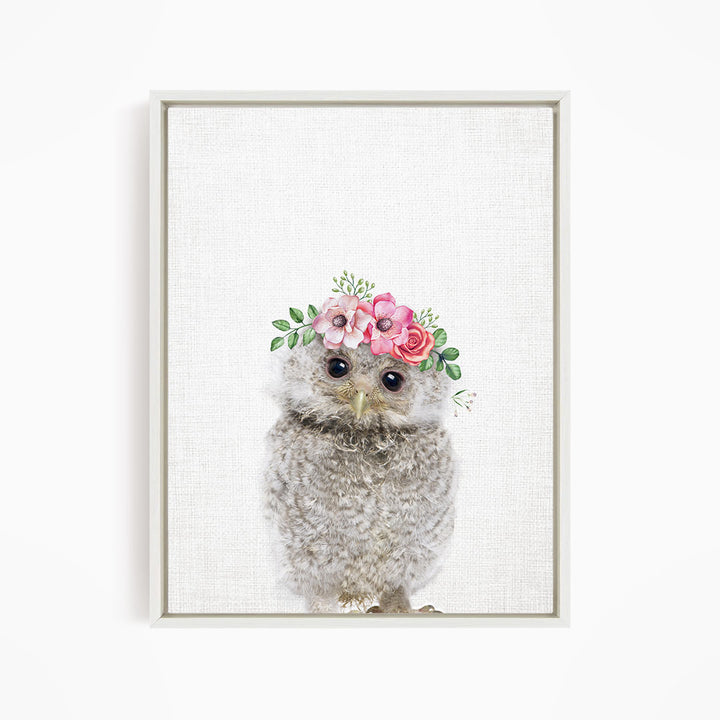 A cute gray owl wearing a floral crown on its head, with pink and white flowers and greenery.