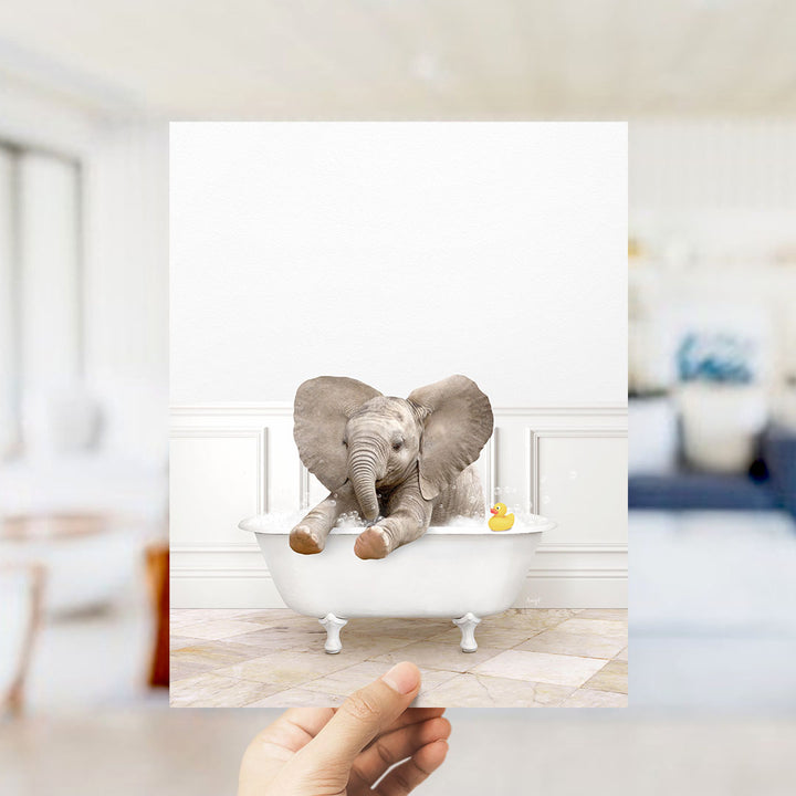 A small elephant sitting in a white bathtub, with a yellow rubber duck floating in the water.
