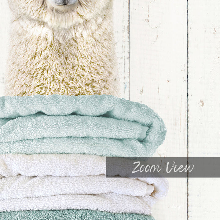 A fluffy white sheep peeking out from behind a stack of light blue and white towels, with the text "Zoom View" overlaid on the image.