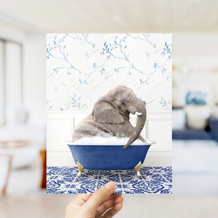 A gray elephant sitting in a blue bathtub filled with bubbles, surrounded by a blue and white floral patterned wall.