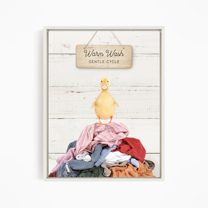 A yellow duck standing on a pile of clothes, with a wooden sign above that reads "Warm Wash Gentle Cycle".
