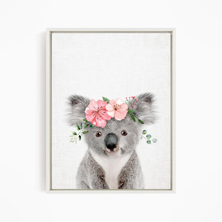A cute koala bear wearing a floral crown of pink flowers and greenery.