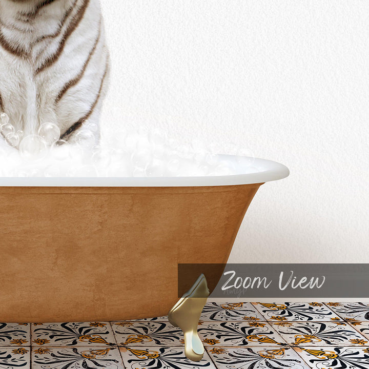 A white and black striped cat standing in a bathtub filled with bubbles, with a gold bathtub leg visible on the floor.
