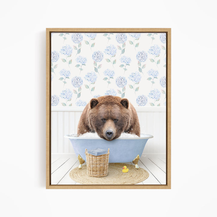 A brown bear is sitting in a blue bathtub filled with water, surrounded by a wicker basket and rubber duckies.