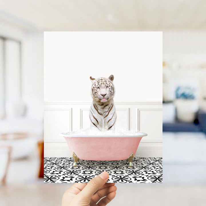 A white tiger sitting in a pink bathtub filled with water, with a hand holding the image up to the viewer.