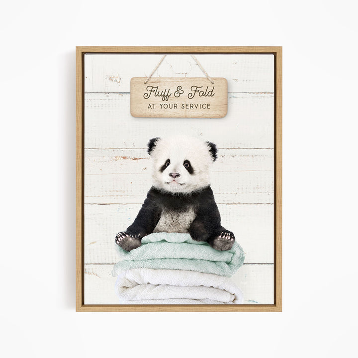 A cute panda bear sitting on a stack of towels, with a wooden sign above that says "Fuffy & Fold at your service".