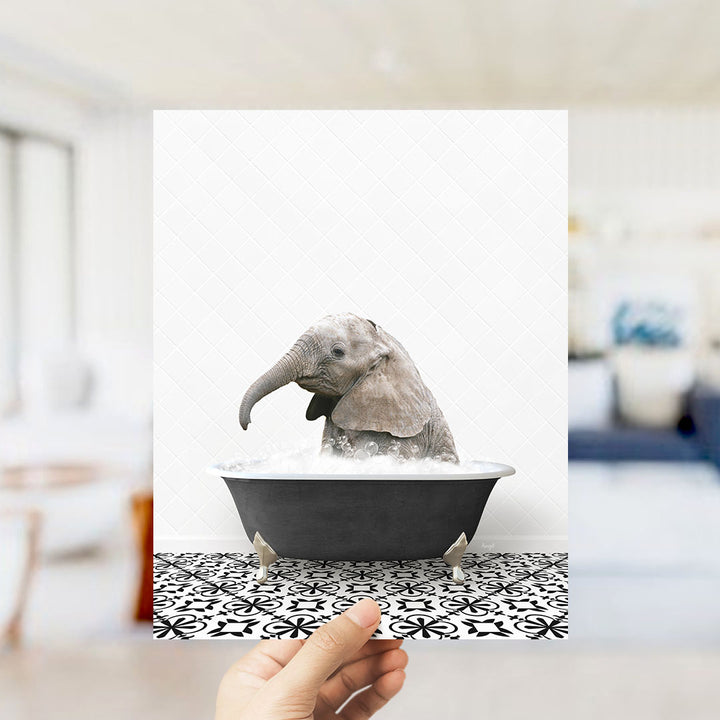 A small gray elephant is sitting in a black bathtub filled with water, creating a whimsical and playful scene.