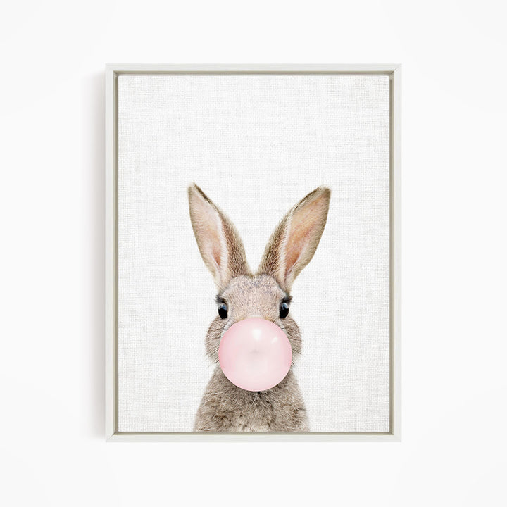 A cute bunny with large ears blowing a pink bubblegum bubble.