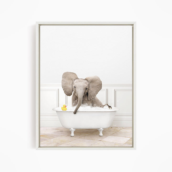 A baby elephant sitting in a white bathtub, with a yellow rubber duck floating nearby.
